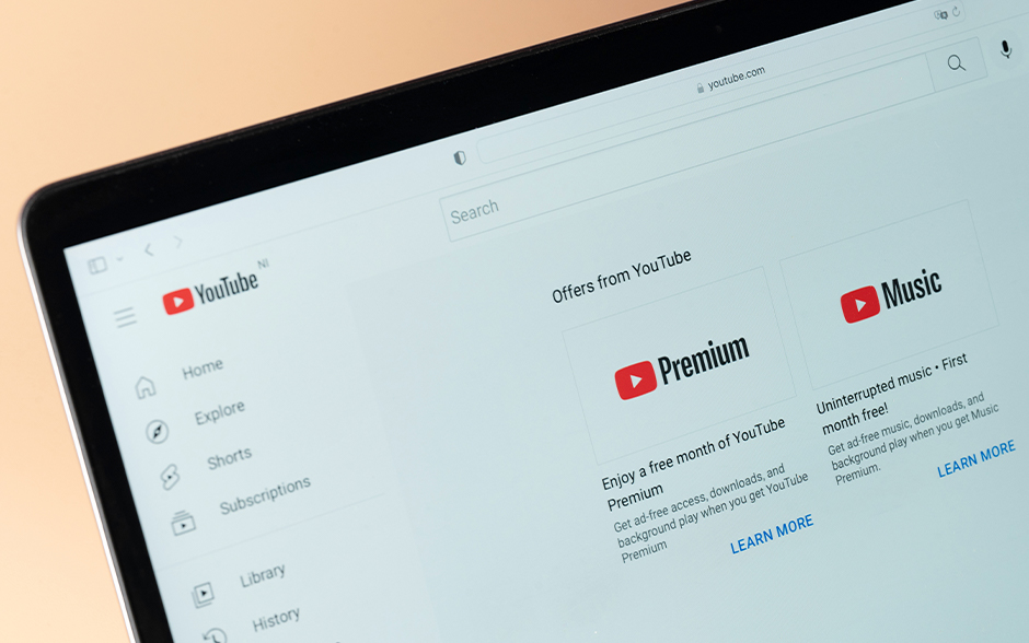 Close-up of a computer screen displaying the YouTube website, highlighting offers for YouTube Premium and Music subscriptions with options to learn more.
