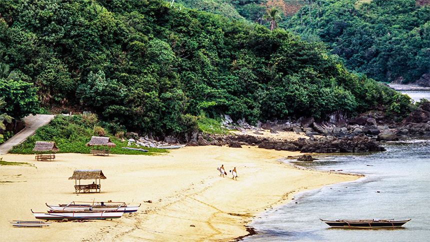 Two surfers walk toward the ocean at a popular surf spot in Catanduanes Island.