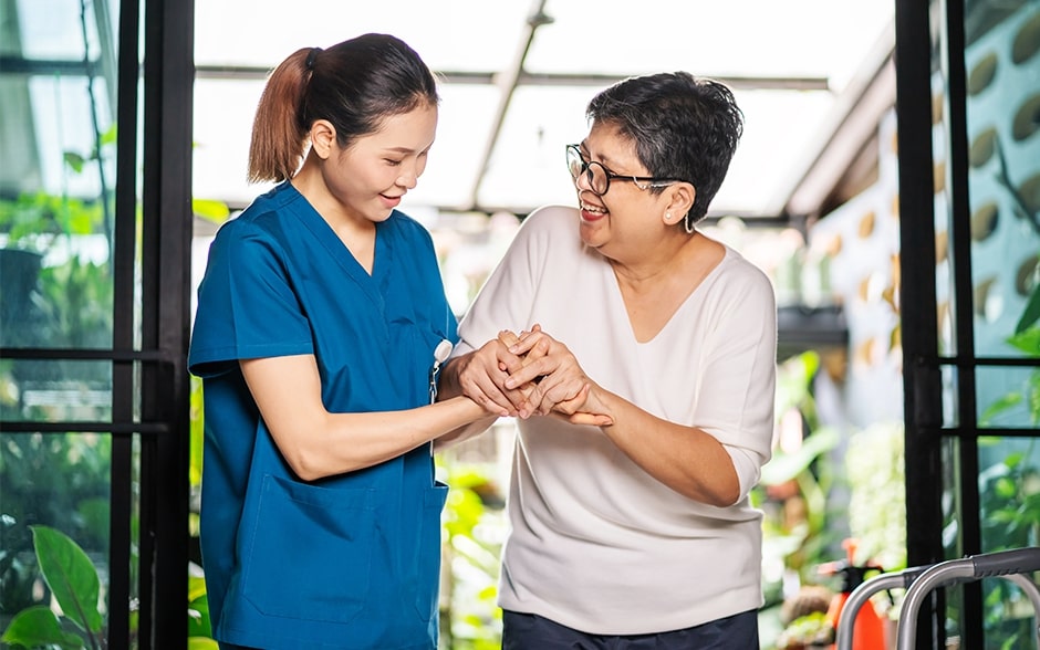 A caregiver shares a joyful moment with a smiling elderly woman.