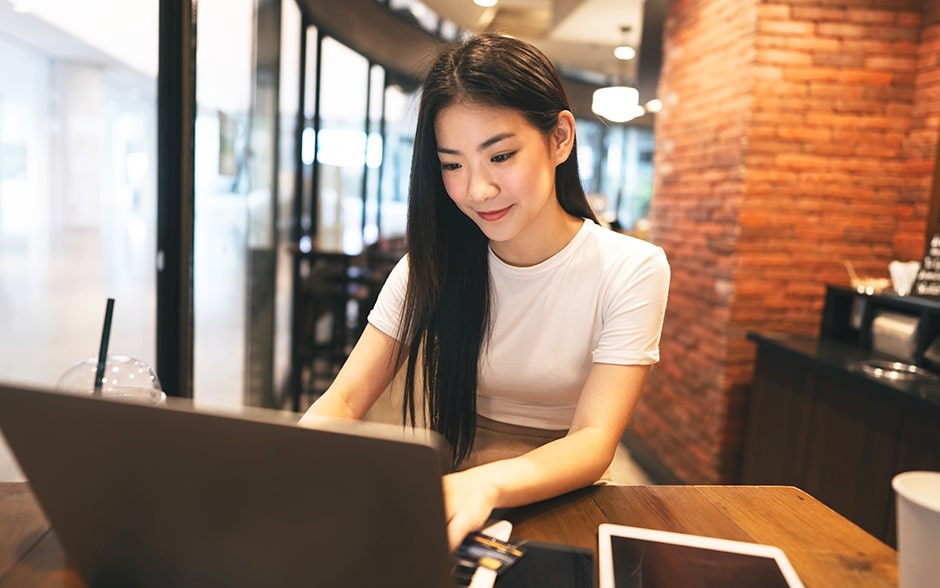 A young woman works on her laptop with a smile in a cozy café.