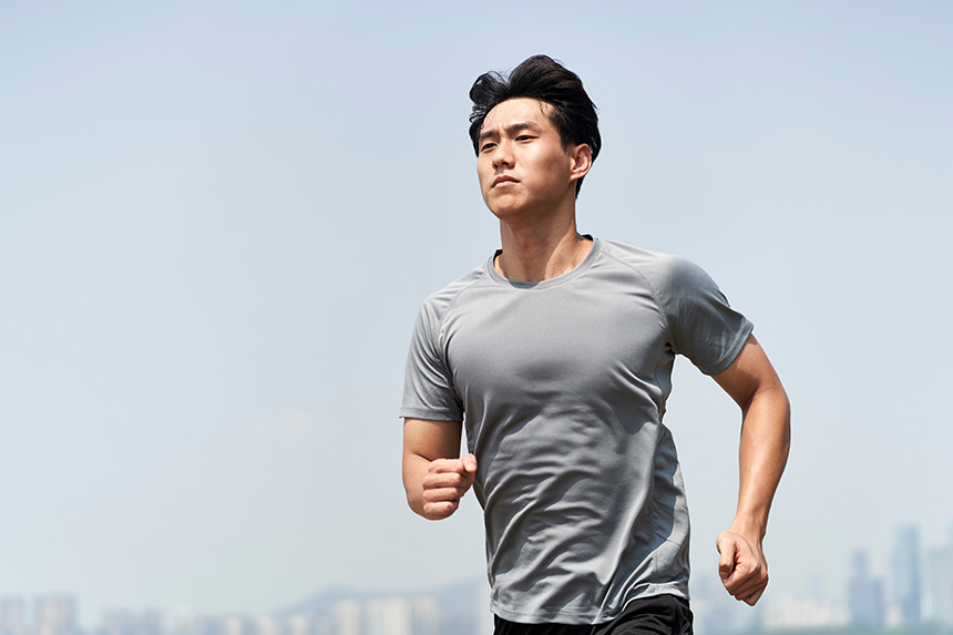 Young Asian man running outdoors.