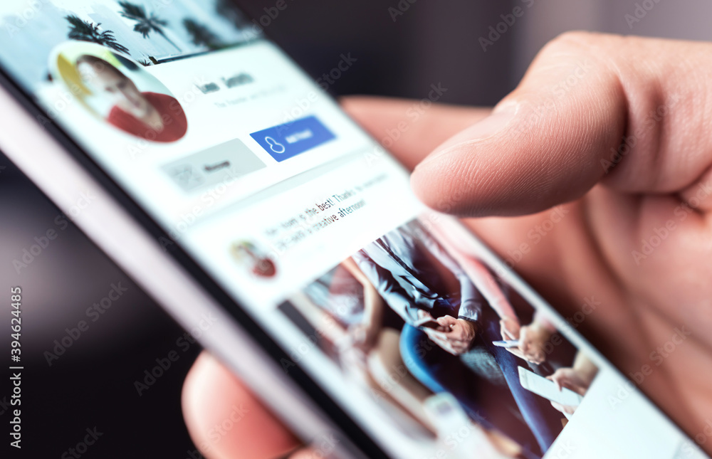 Person interacting with a smartphone showing a social media profile.