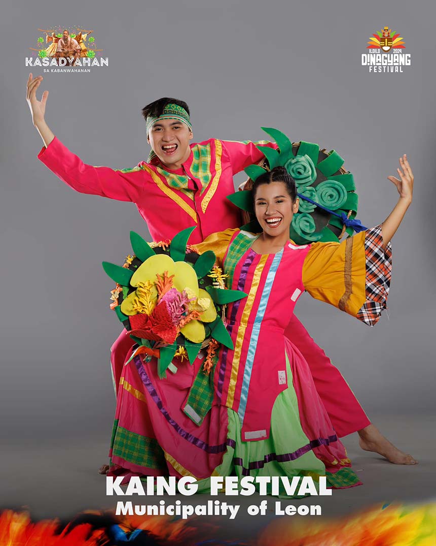Two people in vibrant traditional costumes with floral props, celebrating the Kaing Festival.