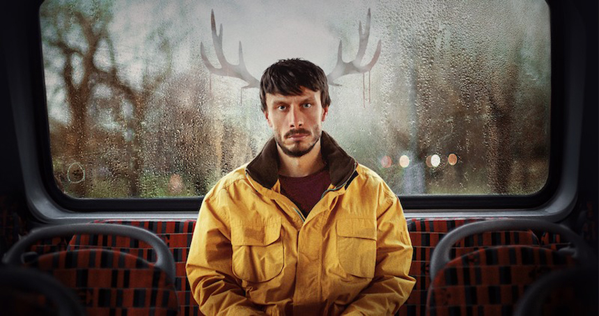 A man in a yellow jacket sits on a bus, with antler-like shapes appearing on the foggy window behind him.