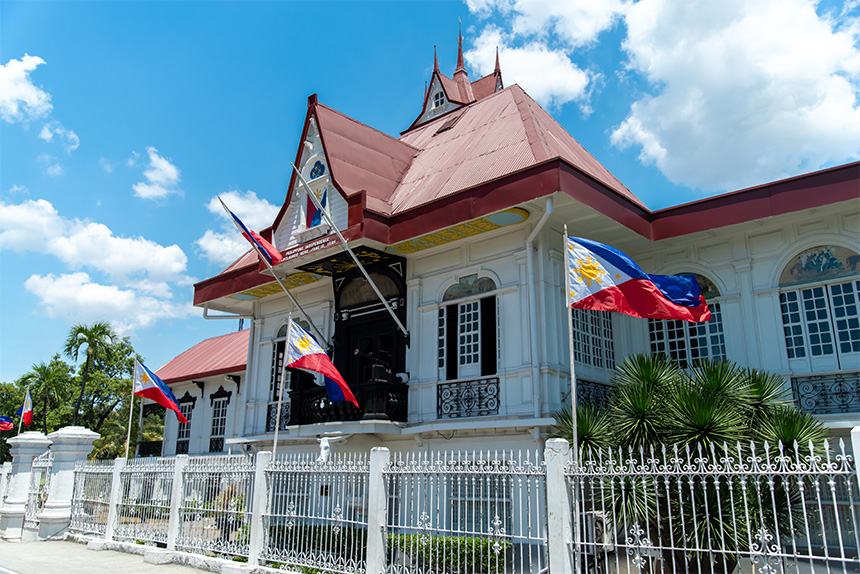 Historic house with red roof and multiple Philippine flags.
