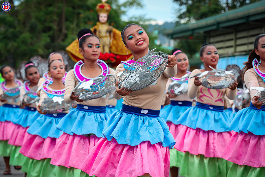 A parade with dancers in colorful outfits holding decorative baskets.