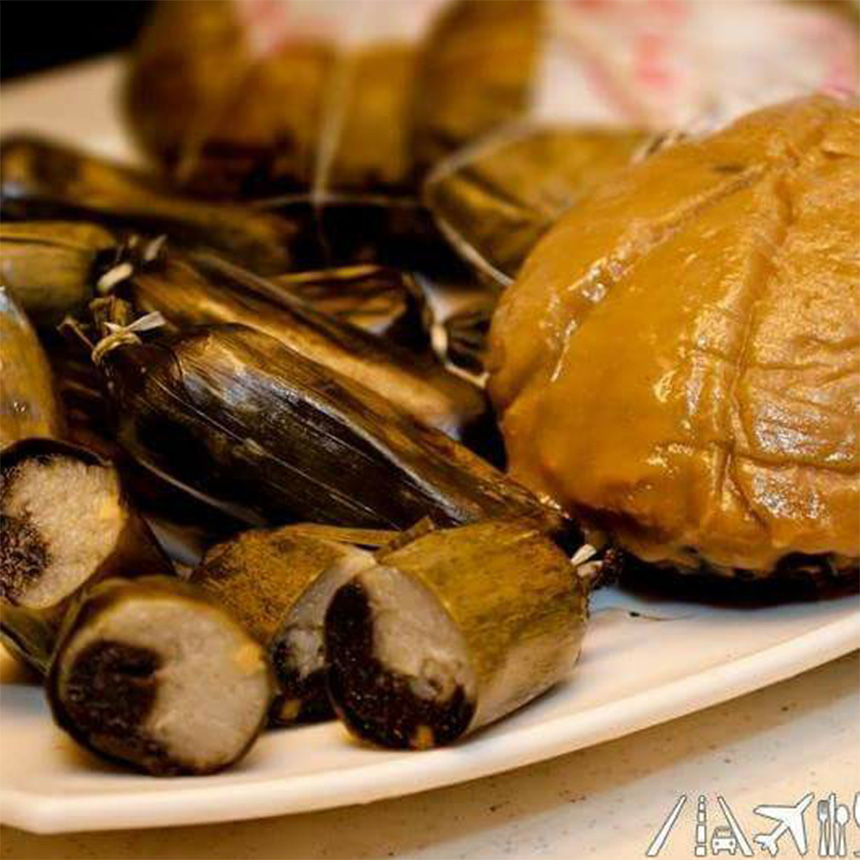 Plate of banana leaf-wrapped rice cakes, with sliced dark glutinous rice and a caramel-topped cake.