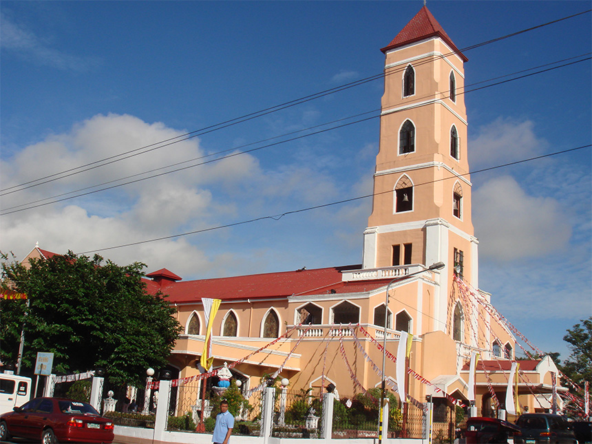 A large peach-colored church with a tall tower, red roof, and surrounded by decorative bunting.