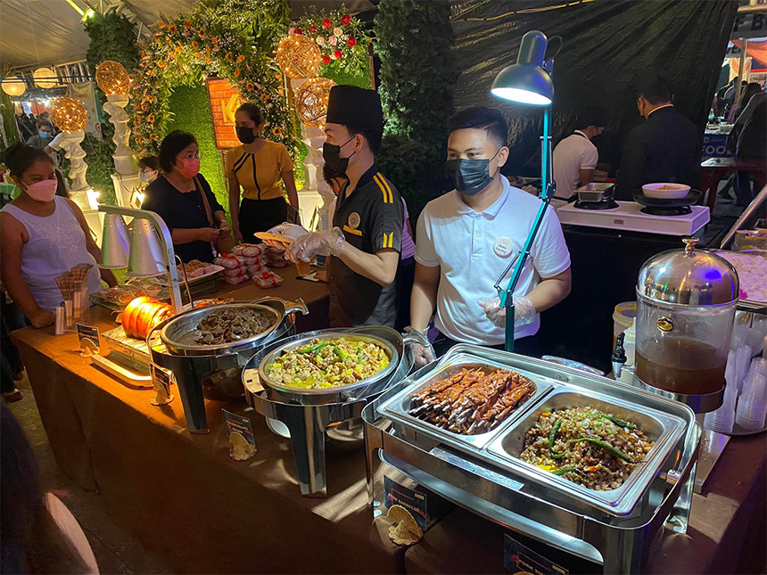Food stall with staff serving various dishes to attending guests at an event.