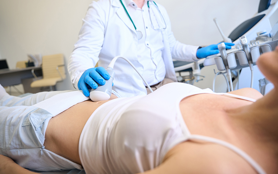 Doctor performing an ultrasound examination on a patient's abdomen in a medical clinic.