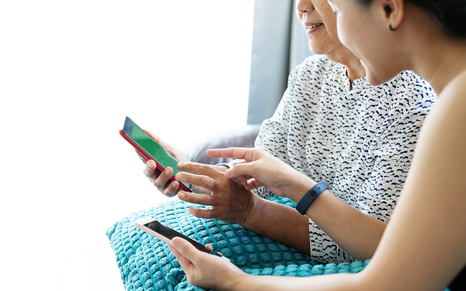 Adult woman and daughter using smartphone together at home