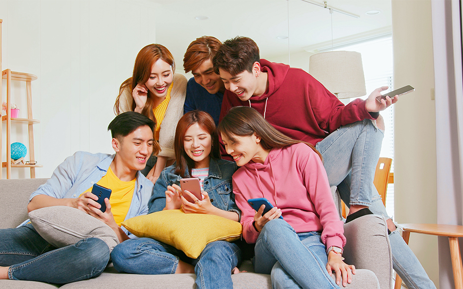 A group of young friends enjoying a fun moment together while looking at their smartphones