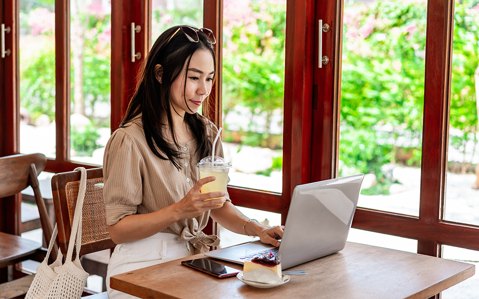 A woman enjoys a drink while working on her laptop in a cozy café