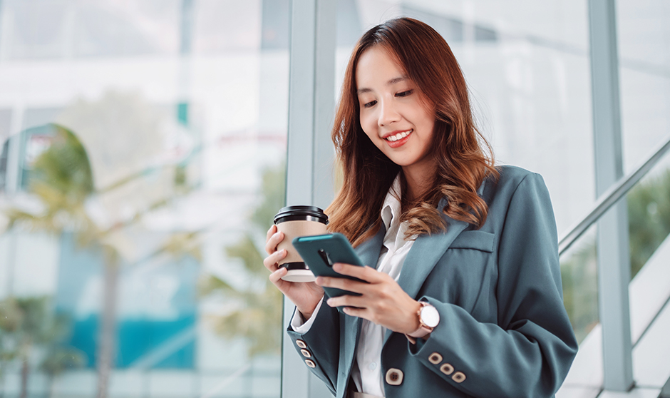 A professional woman in a modern corporate setting confidently using her smartphone, symbolizing productivity and connectivity in the digital age.