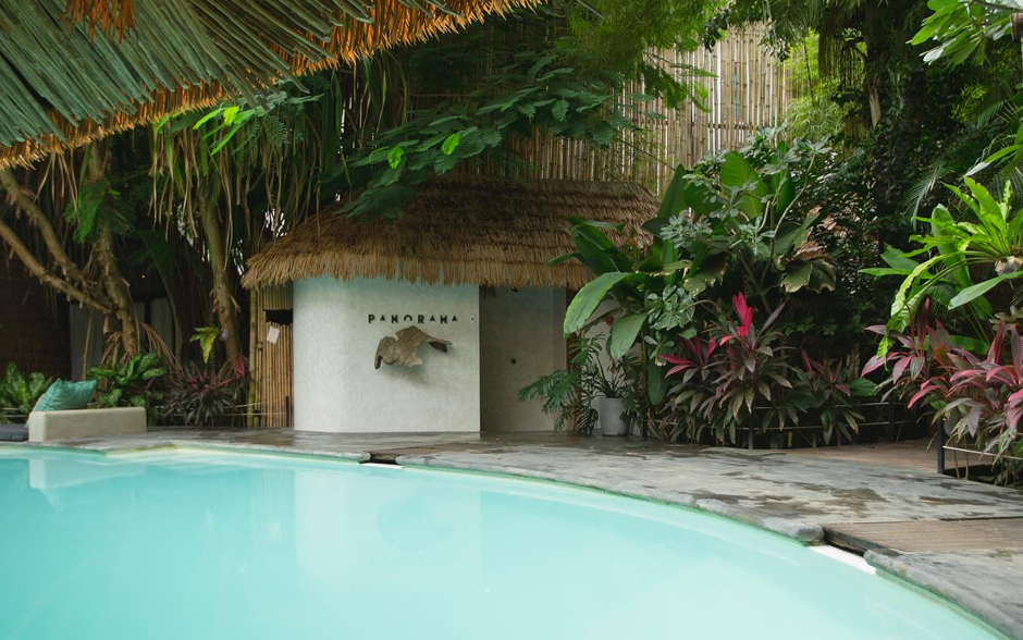 An outdoor pool area with black text on the wall that says "PANORAMA" in the background.