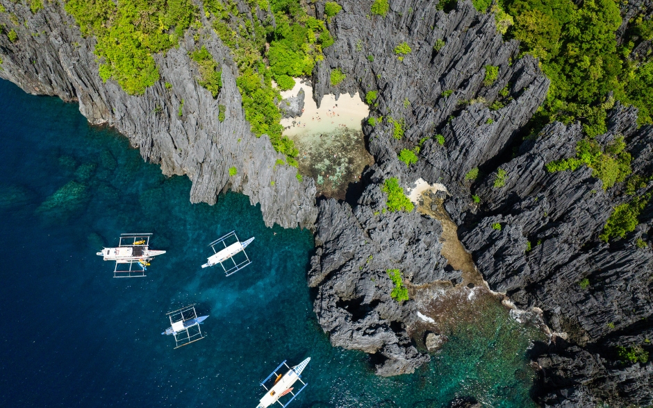 Top view of boats over blue water. Secret Beach in Matinloc, El Nido, Philippines.