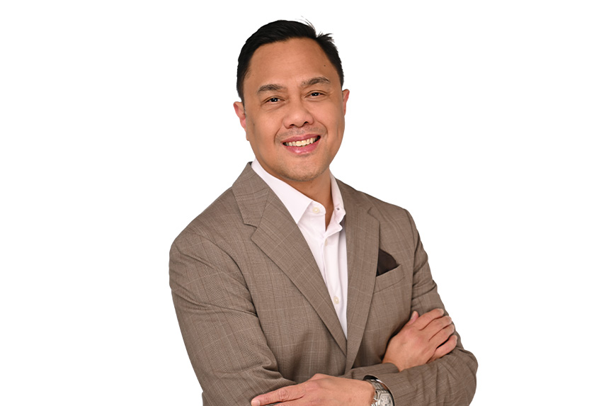 Man in a brown suit with arms crossed, smiling.