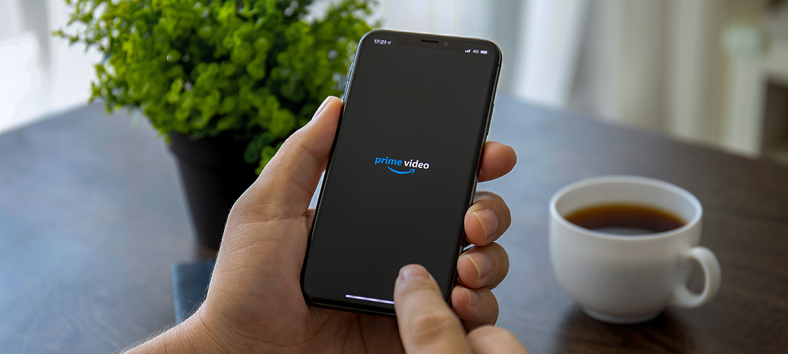 A man holding a smartphone with Amazon Prime Video open on the screen.