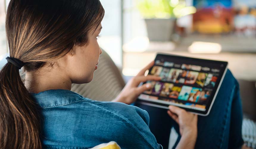 A woman browsing a digital movie catalog on her tablet.